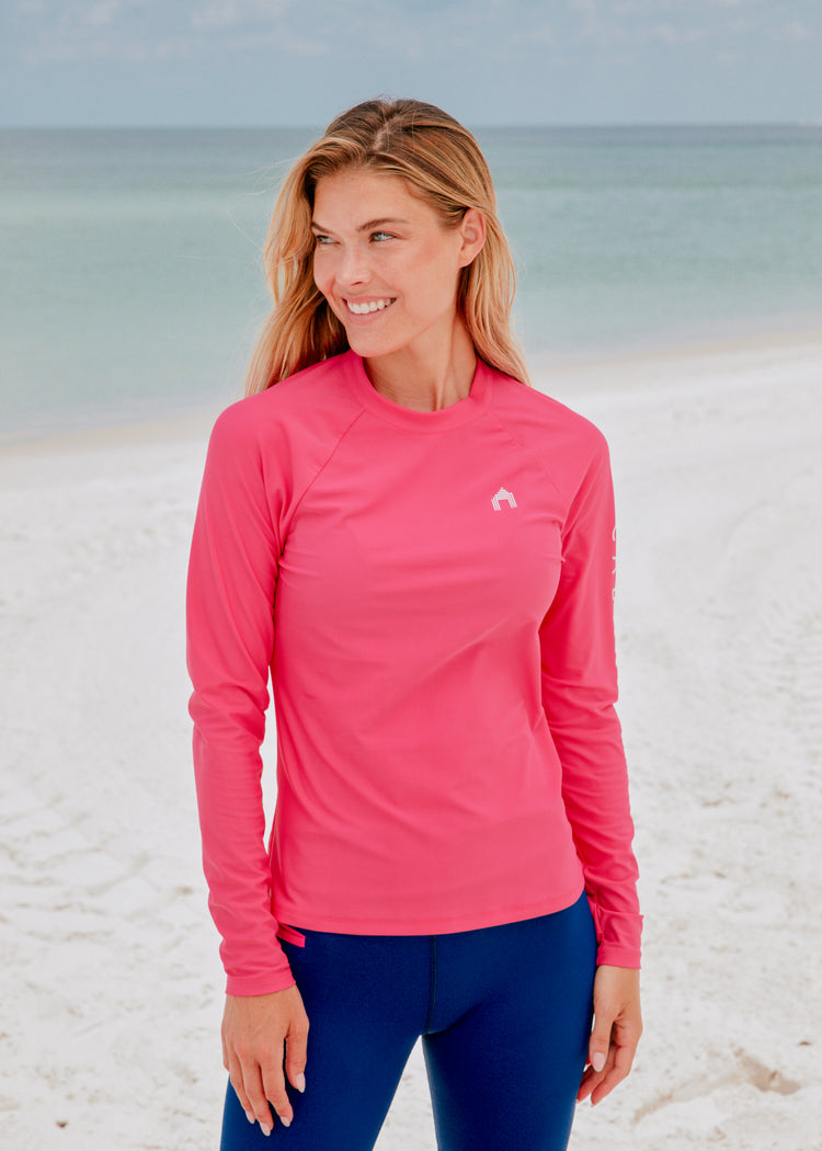 Woman wearing Pink Cabana Life Rashguard on beach.