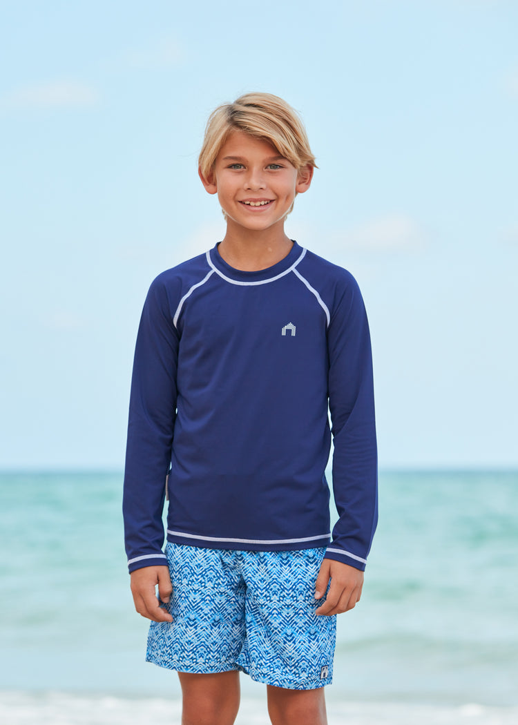 Boy wearing Coral Springs Swim Trunks and Navy Long Sleeve Rash Guard.