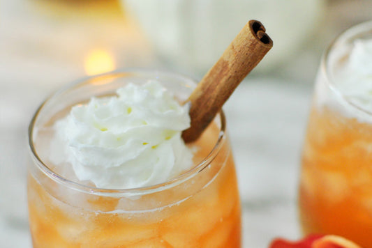 Fall Peach Cobbler Cocktail in glass with whip cream swirl and cinnamon stick garnish