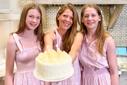 Women in pink dresses holding birthday cake