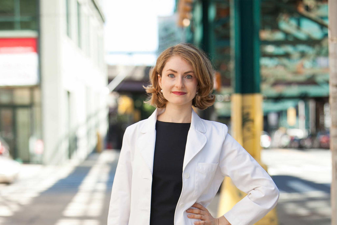 Sophie Greenberg MD Woman wearing white lab coat in front of city background