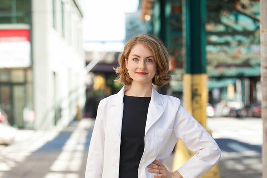 Sophie Greenberg MD Woman wearing white lab coat in front of city background