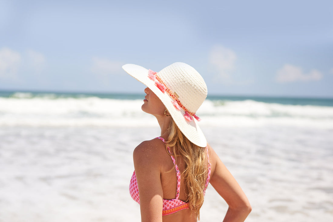 Woman wearing Cabana Life Boca Raton Reversible Bikini Top and hat on beach facing ocean