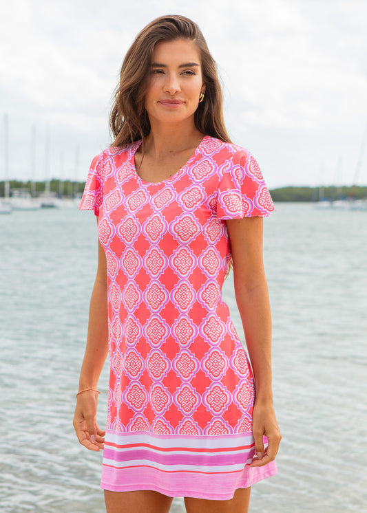 Woman wearing a pink patterned dress by a waterfront