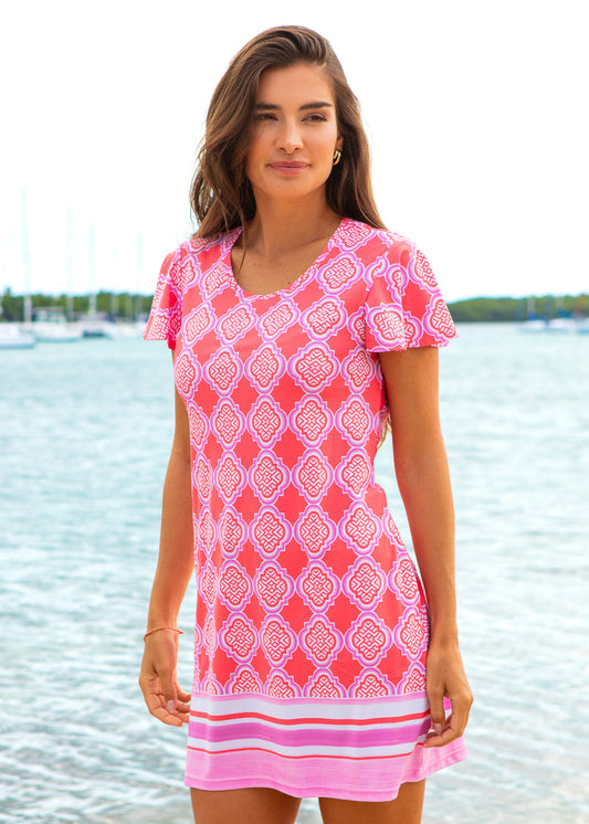 Woman wearing a pink patterned dress by a waterfront