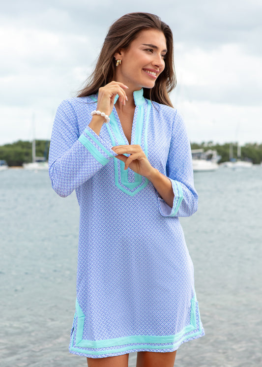 Woman wearing a light blue dress with green trim by a waterfront