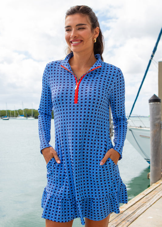Woman wearing a blue checkered dress with a red zipper by a dock with boats.