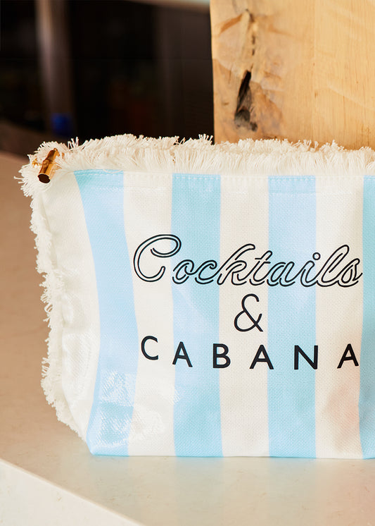 A Cocktails & Cabana Striped Accessory Bag on a white counter.