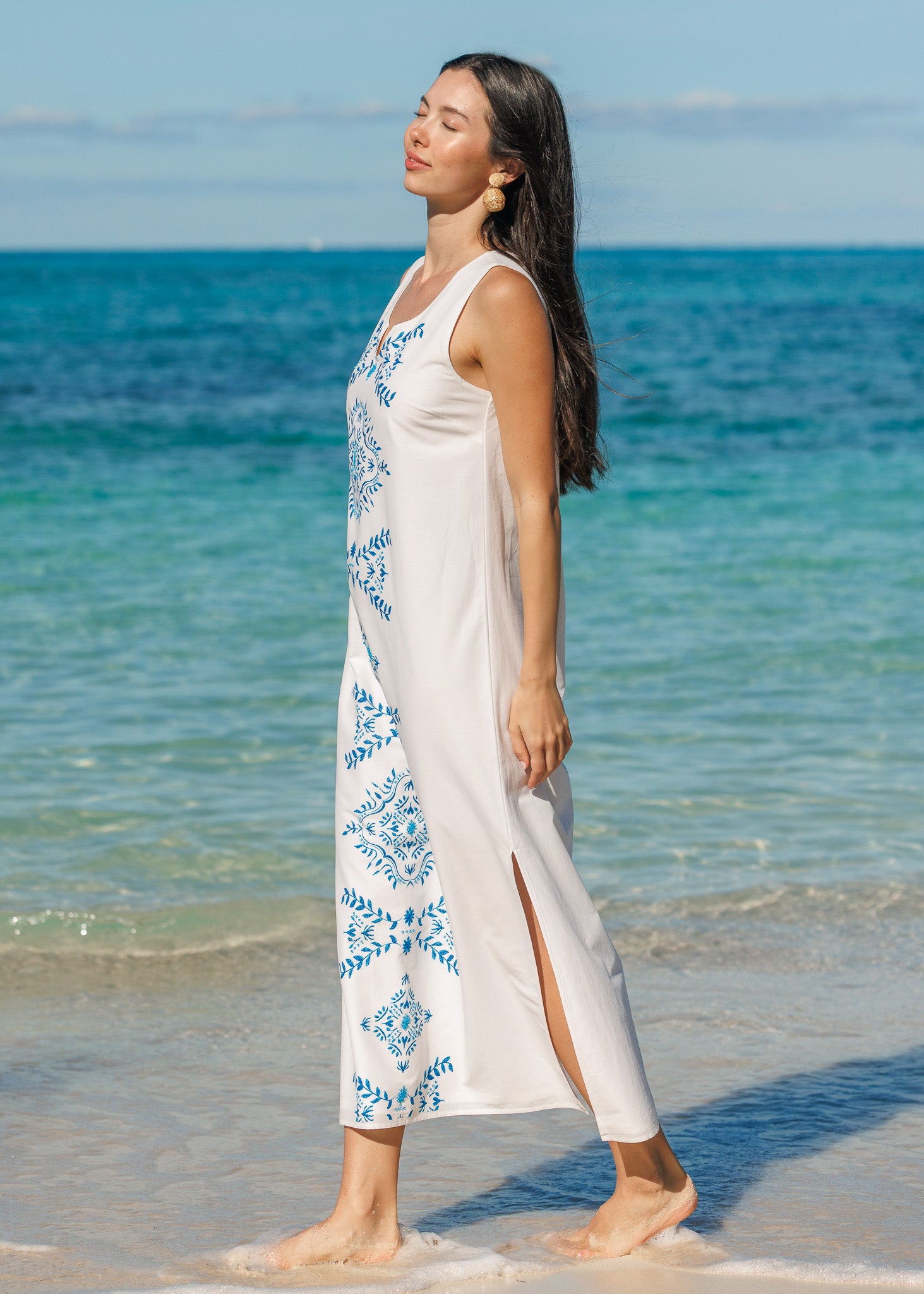 Woman wearing a white maxi dress on the beach.