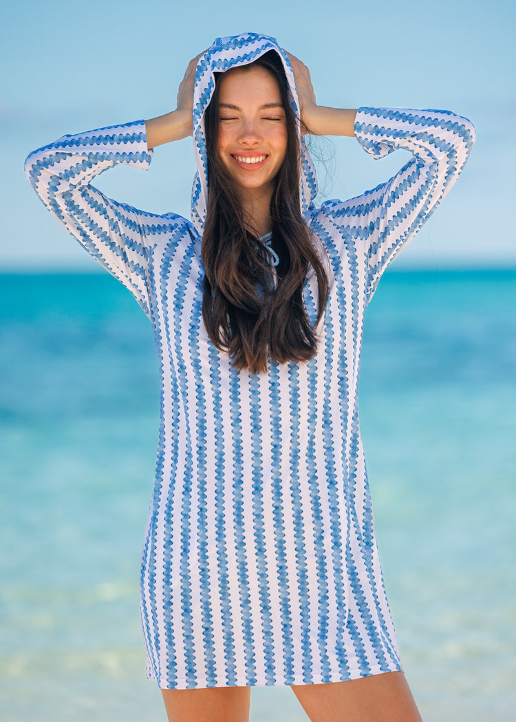 Woman wearing a blue and white striped hooded cover up on a beach