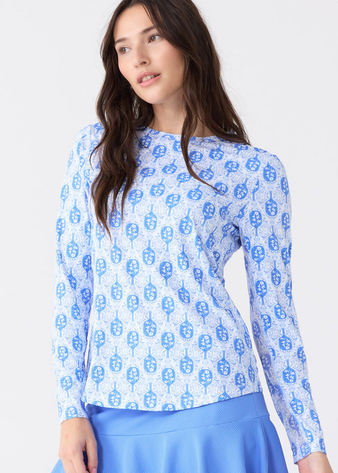 A brunette woman wearing the sun safe Pickleball Long Sleeve Performance Top and Periwinkle 15" Flounce Skort from Cabana Life.