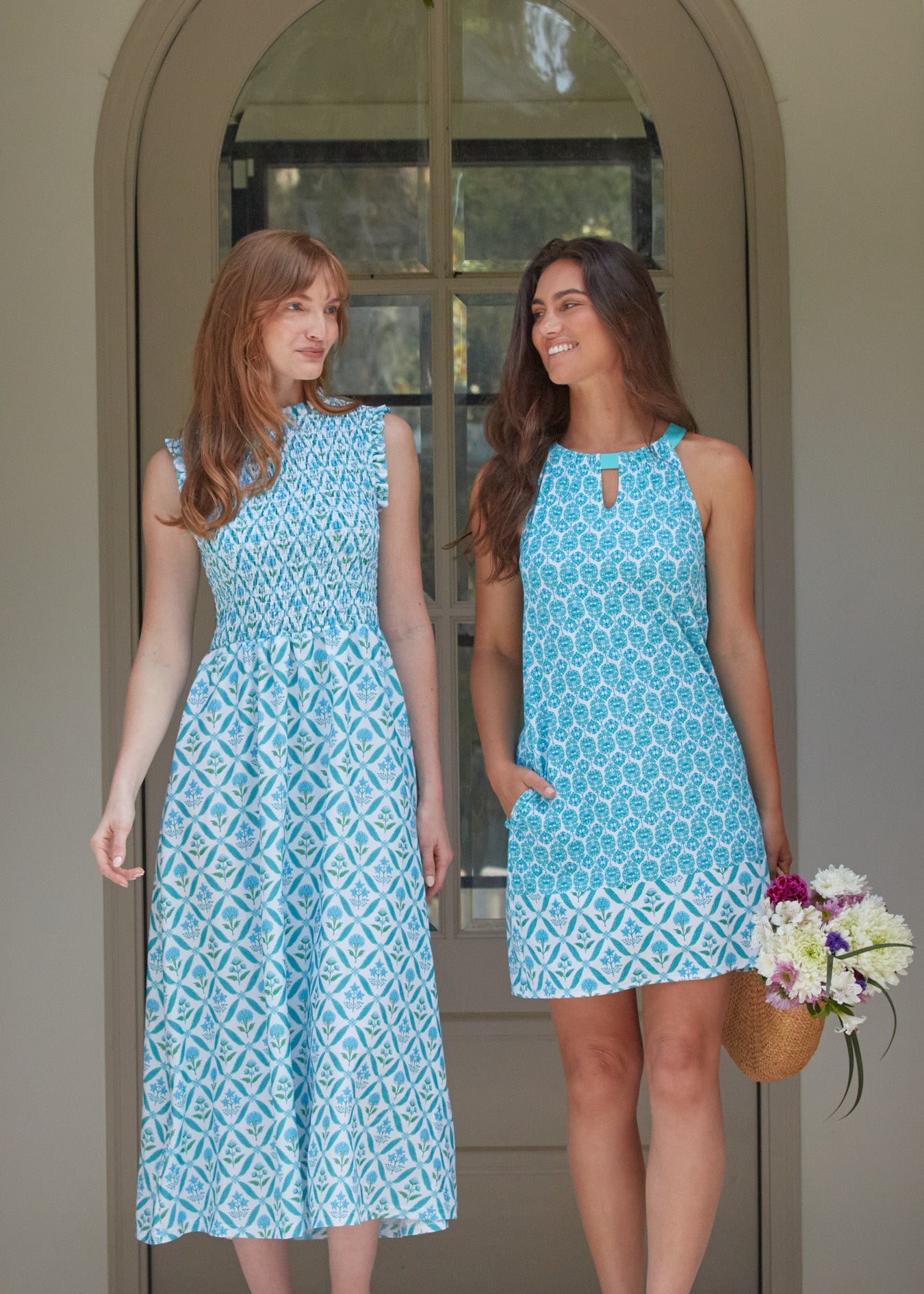 A redhead woman wearing the Cabana Life sun protective Rosemary Beach Smocked Maxi Dress walking with a brunette woman in the Rosemary Beach Sleeveless Shift Dress.