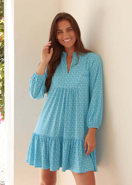 A brunette woman wearing the Cabana Life sun protective Rosemary Beach Relaxed Dress against a wall.