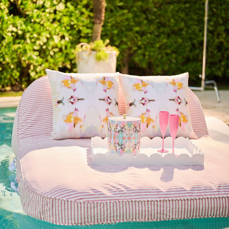 Pillow with butterfly pattern on a pool float with drinks and a candle