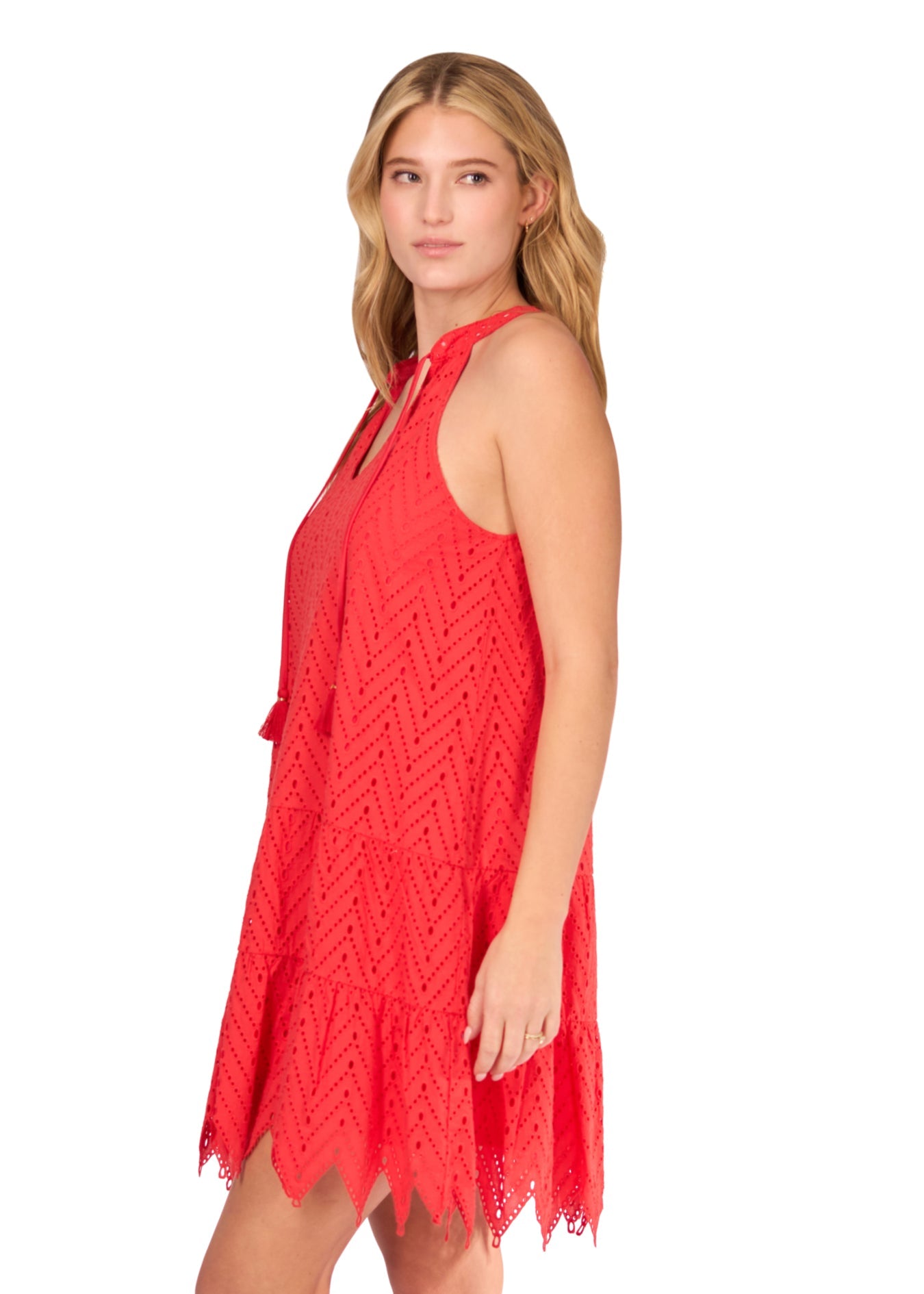 The side of a blonde woman in front of a white background wearing the Poppy Red Eyelet Halter Dress.