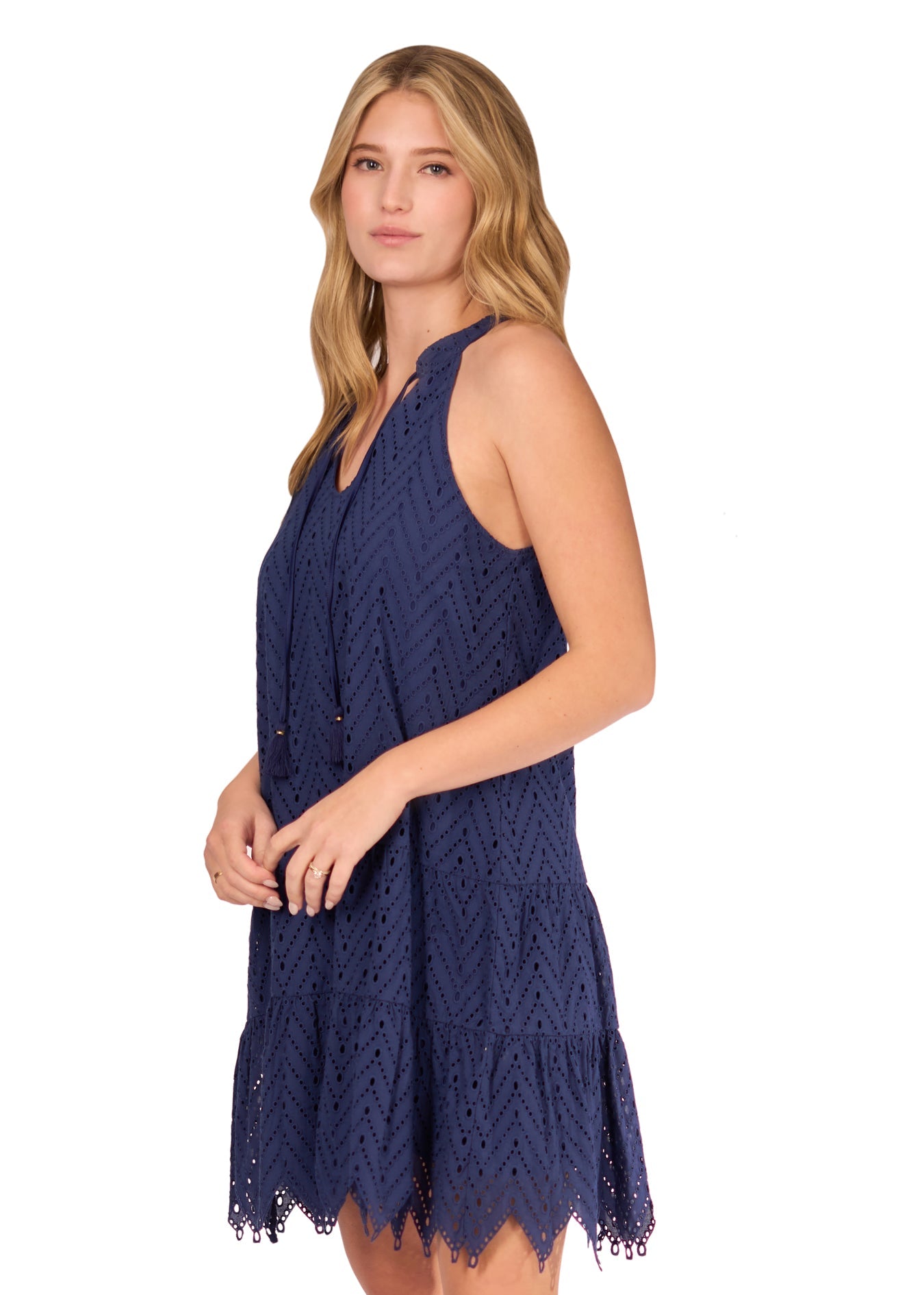 The side of a blonde woman wearing the Navy Eyelet Halter Dress on a white background.
