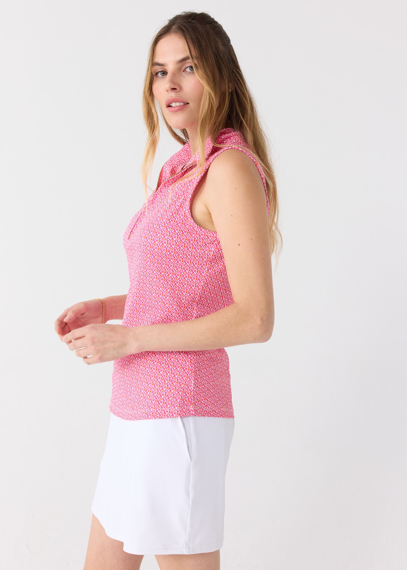 The side of a blonde woman wearing the Cabana Life sun safe Amelia Island 1/4 Zip Sleeveless Sport Top with a White 15" Skort.