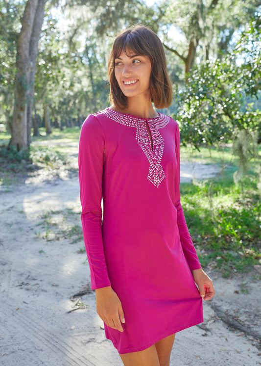 Side of brunette woman with short hair and bangs wearing Merlot Metallic Key Hole Dress.on a dirt road in front of a grassy field.