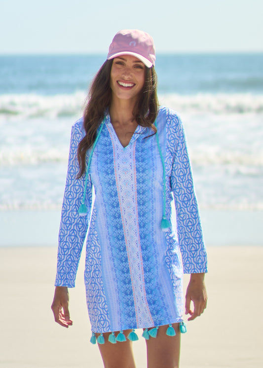 Woman wearing Lake Como Hooded Tunic Dress with Pink Cabana Life Baseball Hat holding tassels on beach.