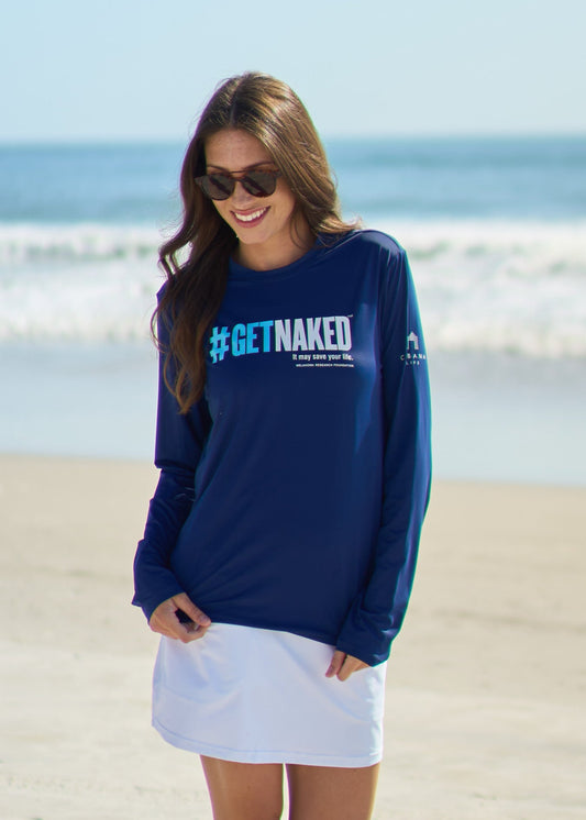 A brunette woman looking down wearing the Get Naked Unisex Performance Shirt and White Skort on the beach.