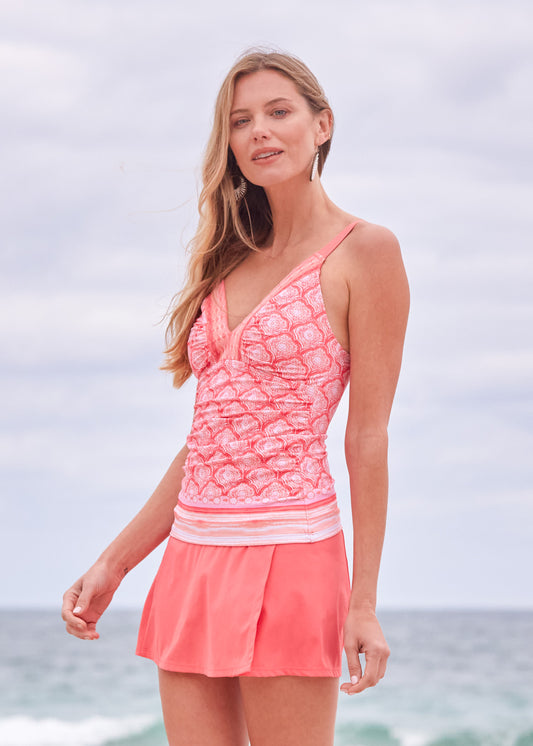 A blonde woman wearing the Cabana Life sun protective Amelia Island Embroidered Tankini Top and Coral Classic Swim Skirt on the beach.