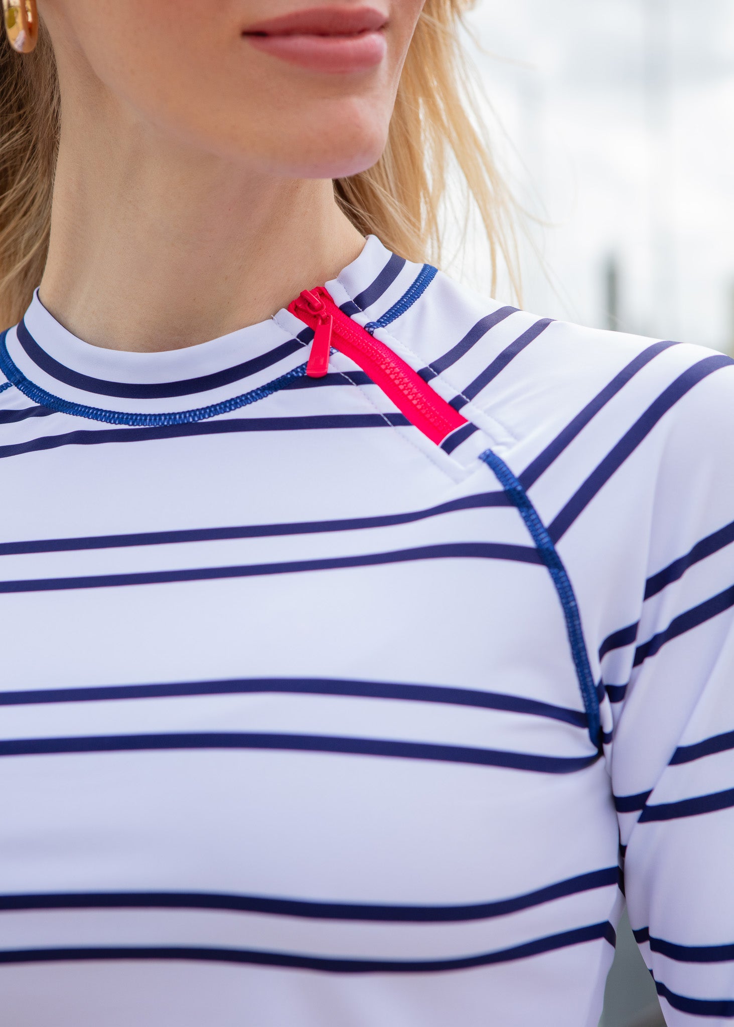 Close-up of a person wearing a white and blue striped shirt with a red zipper detail.
