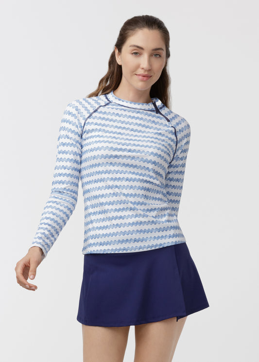 Woman wearing a blue and white striped long-sleeve top and navy skirt on a light gray background