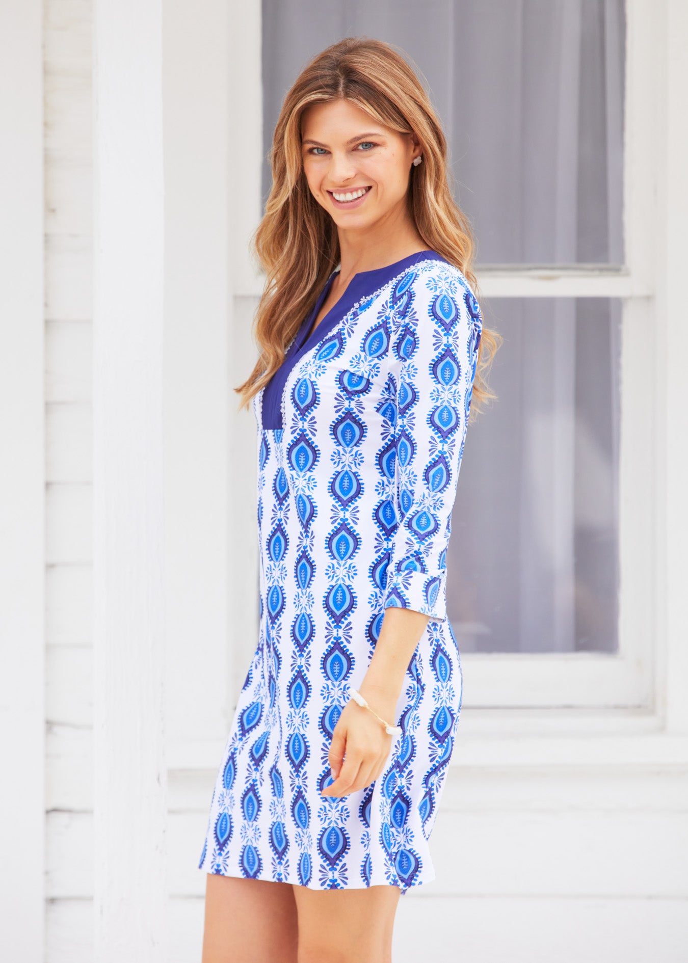 Side of woman wearing San Sebastian Embroidered Tunic Dress against white building