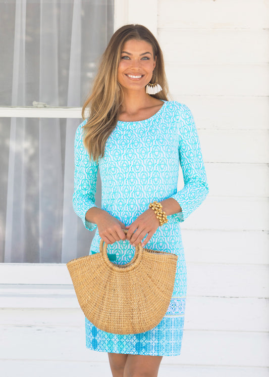 Woman wearing Coastal Cottage Cabana Shift Dress holding a straw bag.