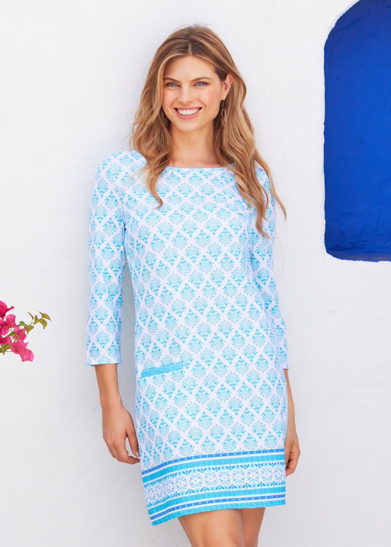 Blonde woman leaning against wall wearing Amalfi Coast Cabana Shift Dress. 