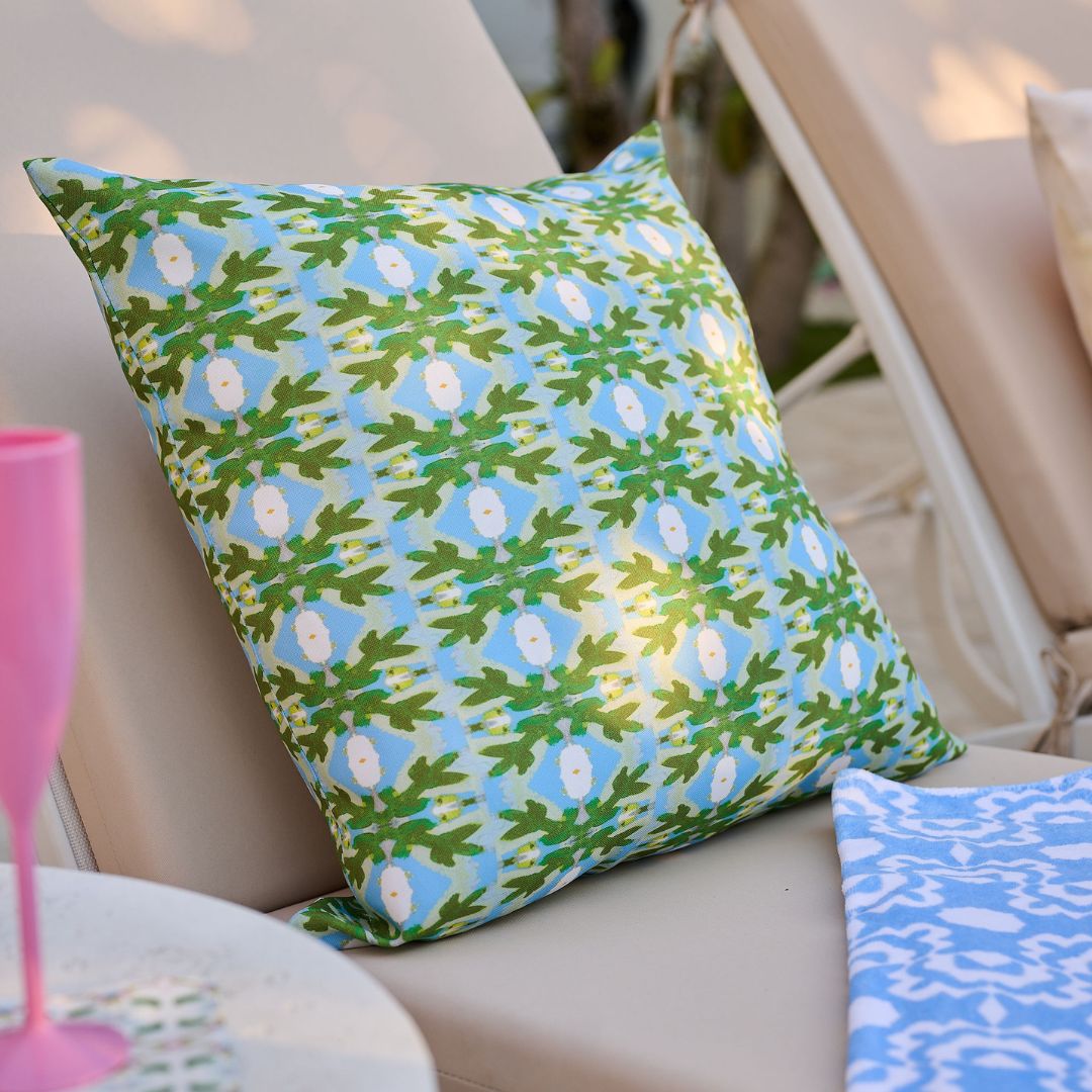 Decorative pillow with a green and blue pattern on a beige chair.