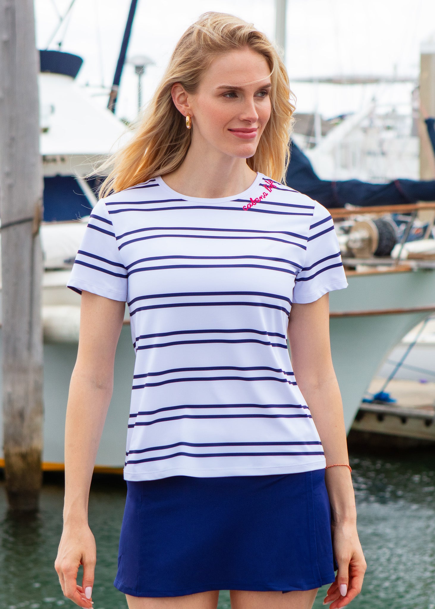 Woman wearing a striped shirt and blue skirt by a marina