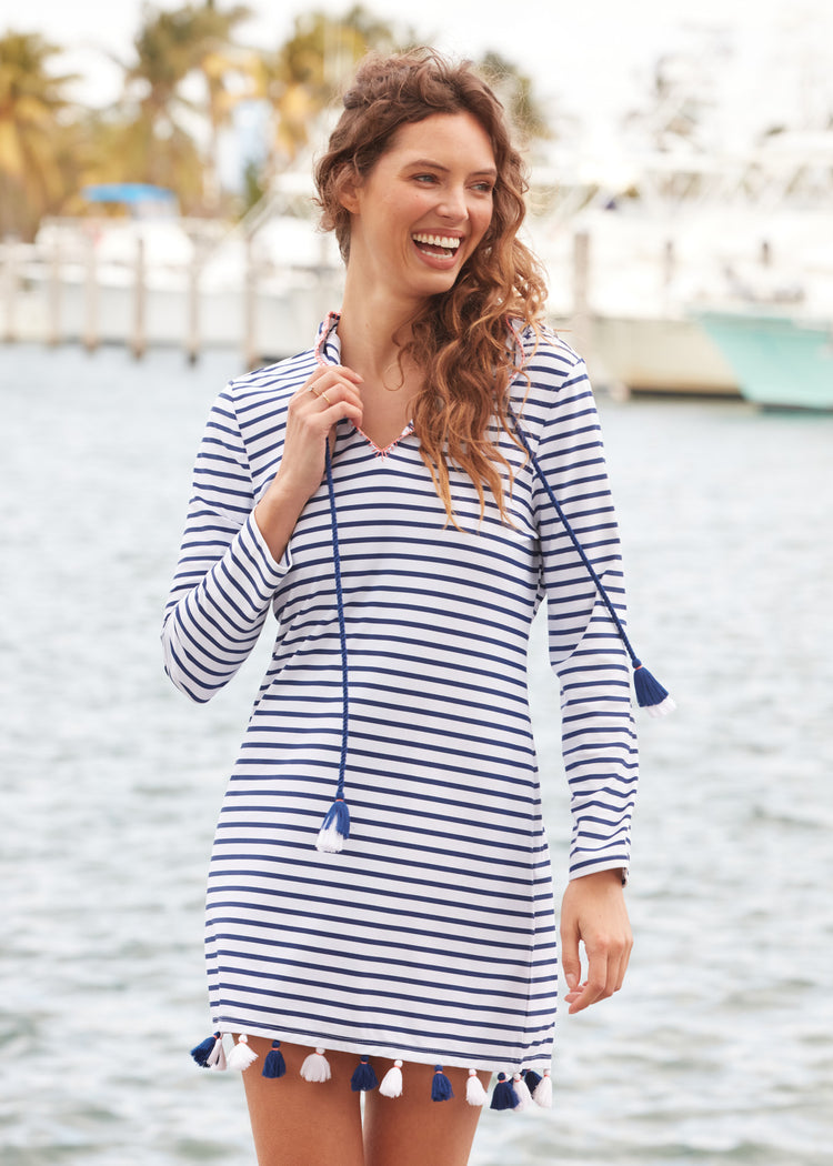 Brunette with curly hair holding collar of Navy Stripe Hooded Cover Up in front of marina.
