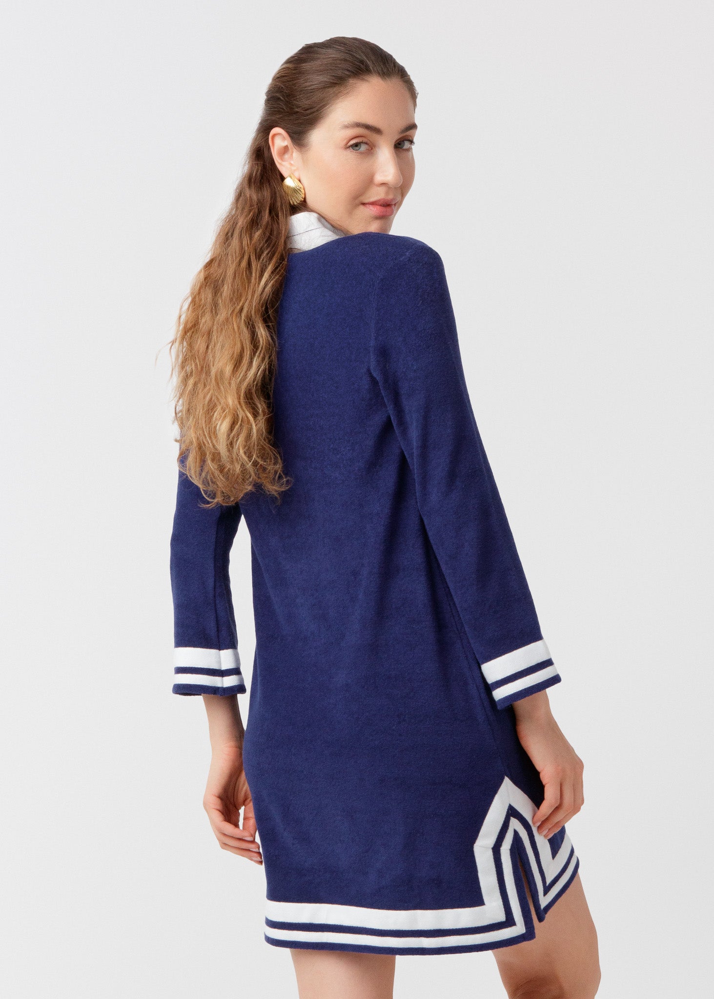 Woman wearing a blue dress with white trim on a plain background