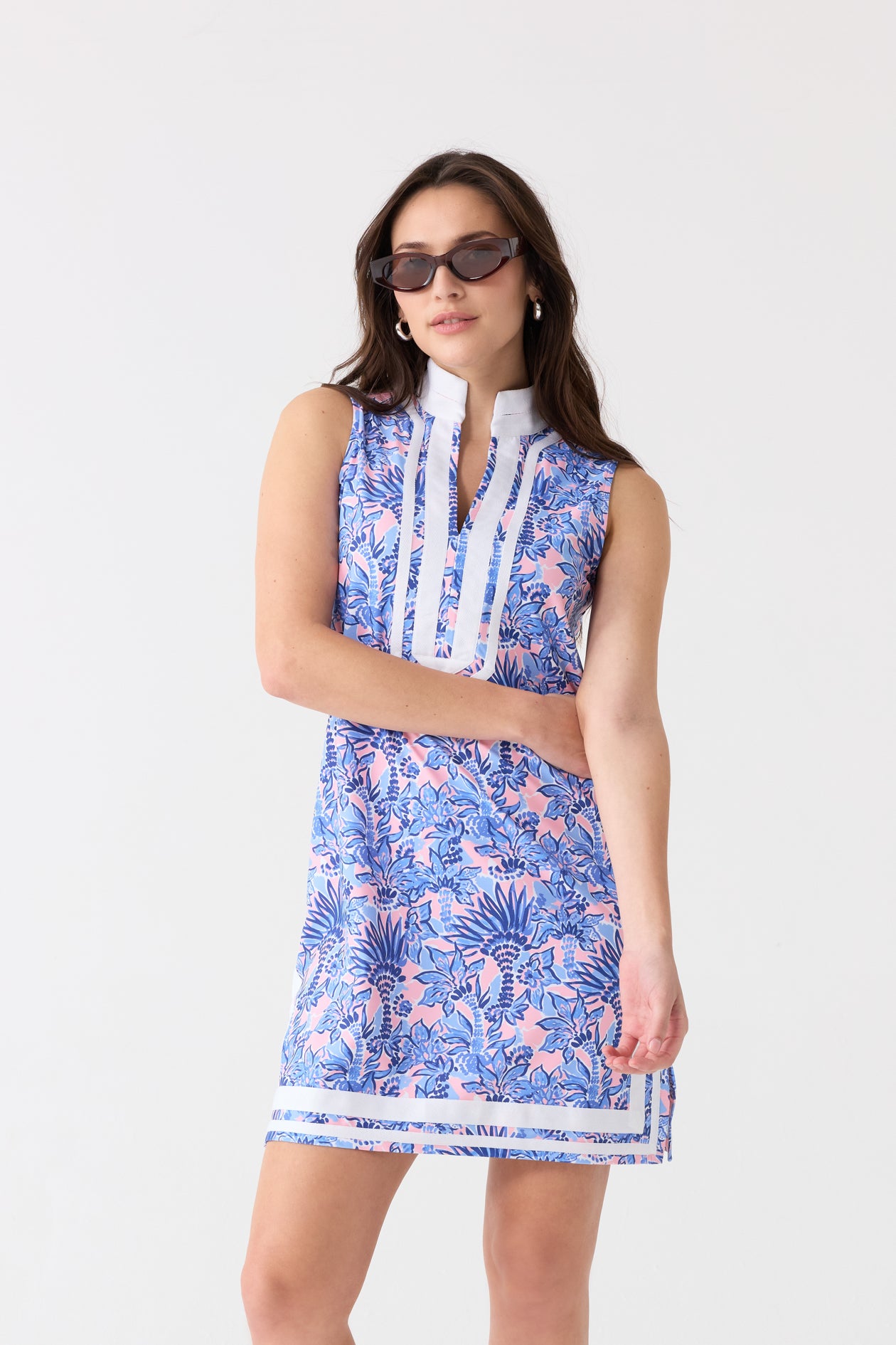 A brunette woman wearing dark sunglasses and the Cabana Life sun protective Palm Beach Sleeveless Tunic Dress with her arm over her.