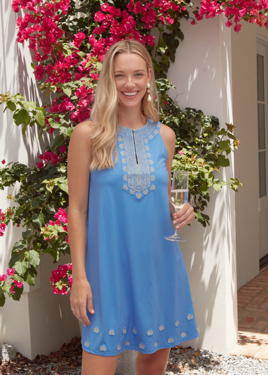Woman wearing a blue dress with gold embroidery.