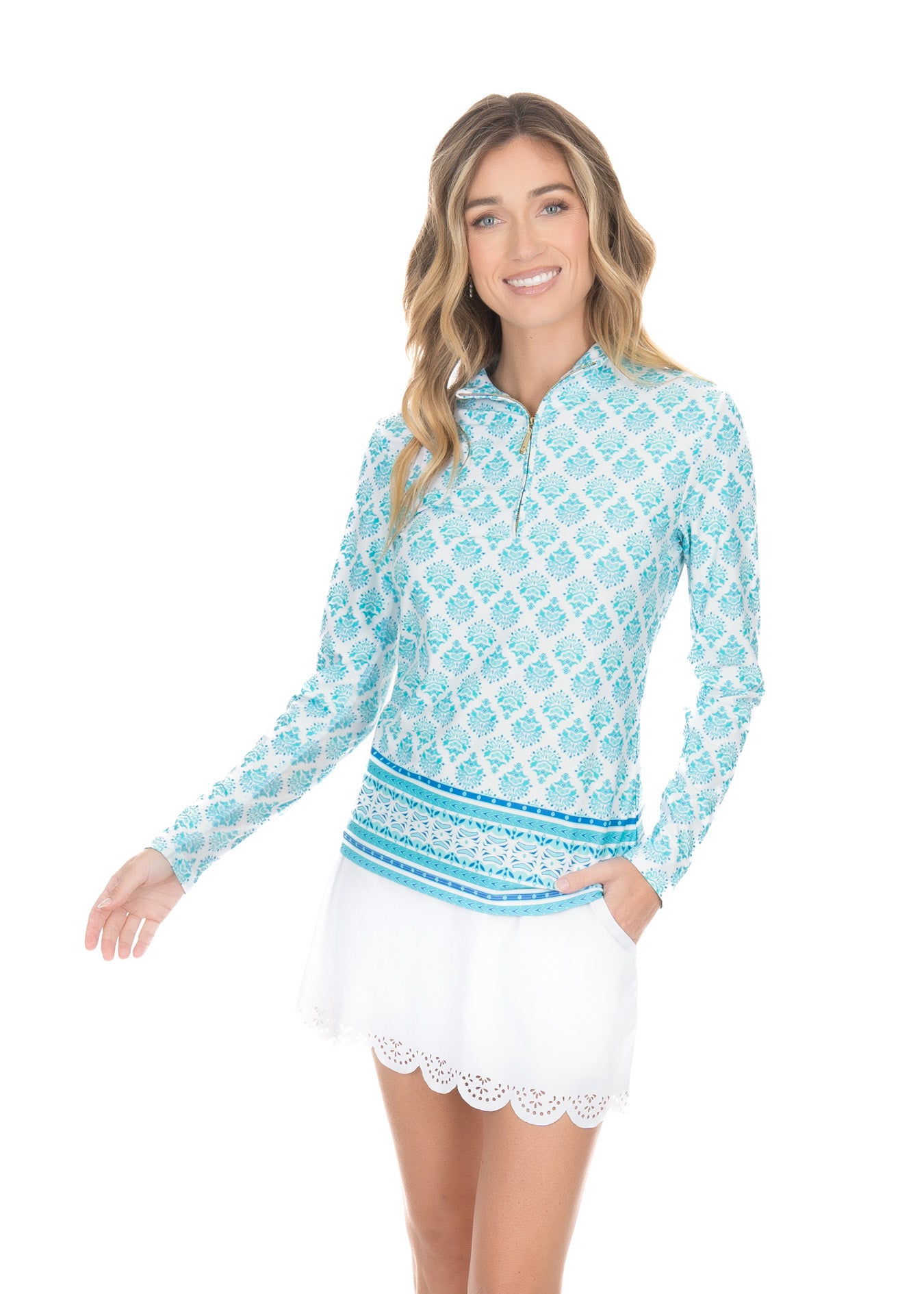 Blonde woman wearing Amalfi Coast 1/4 Zip Sport Top with white scalloped skort in front of a white background.