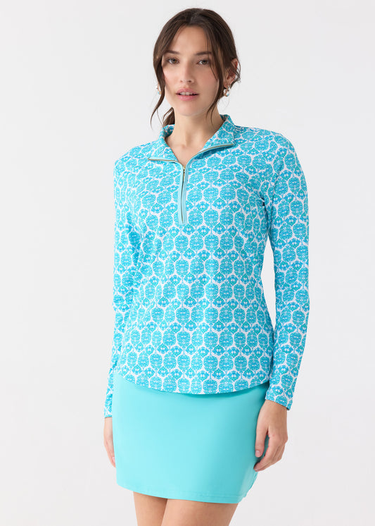 A brunette woman wearing the Cabana Life sun protective Rosemary Beach Performance 1/4 Zip Sport Top with mesh underarms, paired with the Aqua 17" Skort.