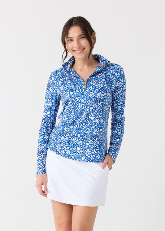 A dark haired woman wearing the Cabana Life sun protective Seaside Floral 1/4 Zip Sport Top and White 17" Skort.