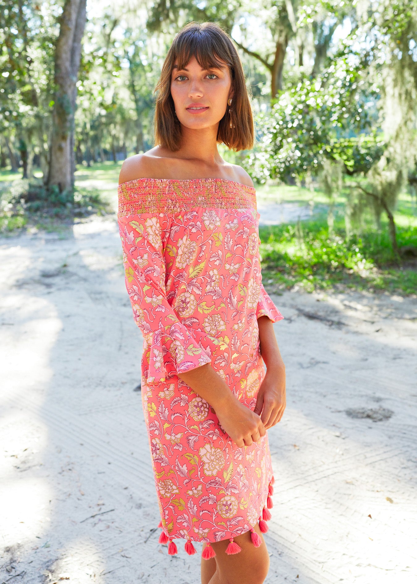 Side of brunette woman wearing Coral Metallic Off The Shoulder Dress.