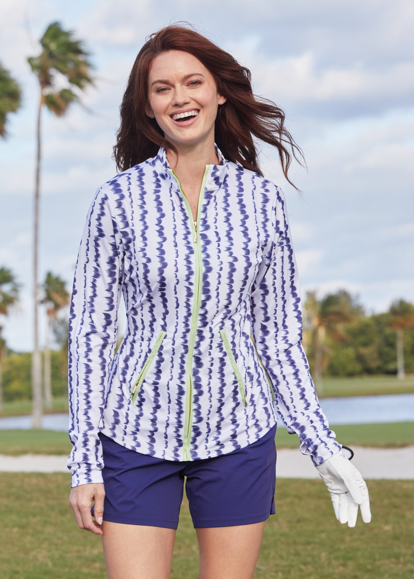 A woman laughing on a golf course wearing the sun protective Navy Performance Short from Cabana Life.