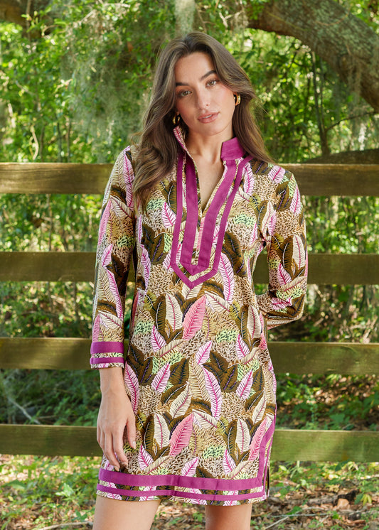 Woman wearing a patterned dress with a pink collar and trim, standing outdoors.