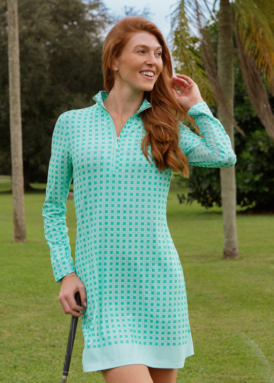 Woman wearing a green basketweave dress standing on a golf course.