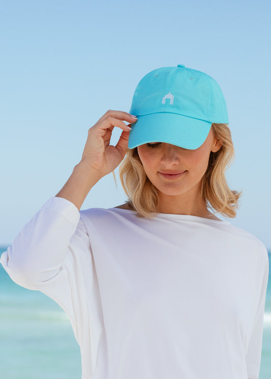 Blonde woman looking down wearing Aqua Cabana Life Baseball Hat with white rashguard