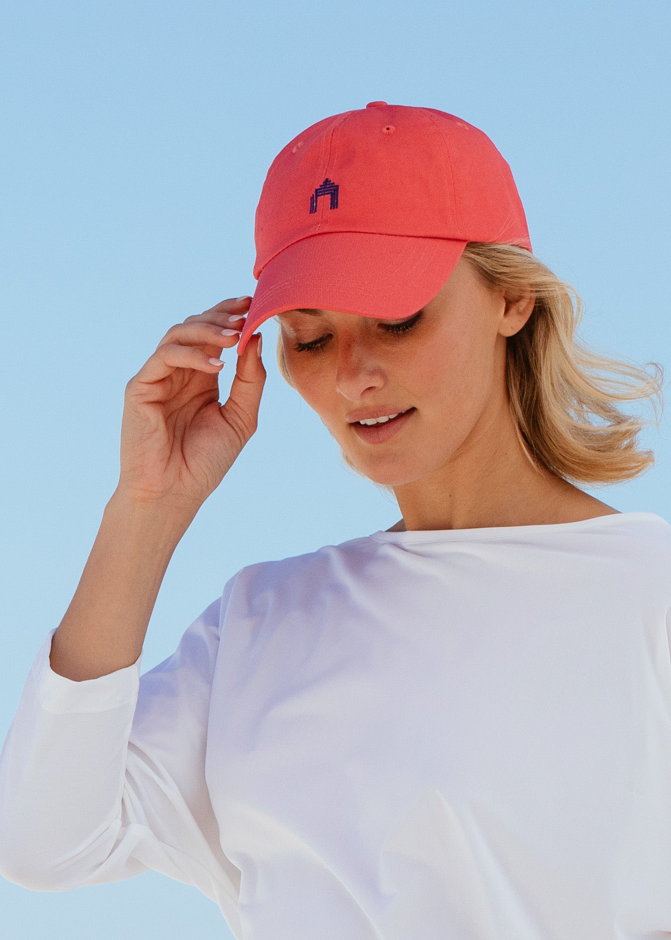 Blonde woman looking down wearing Nantucket Red Cabana Life Baseball Hat with white rashguard.
