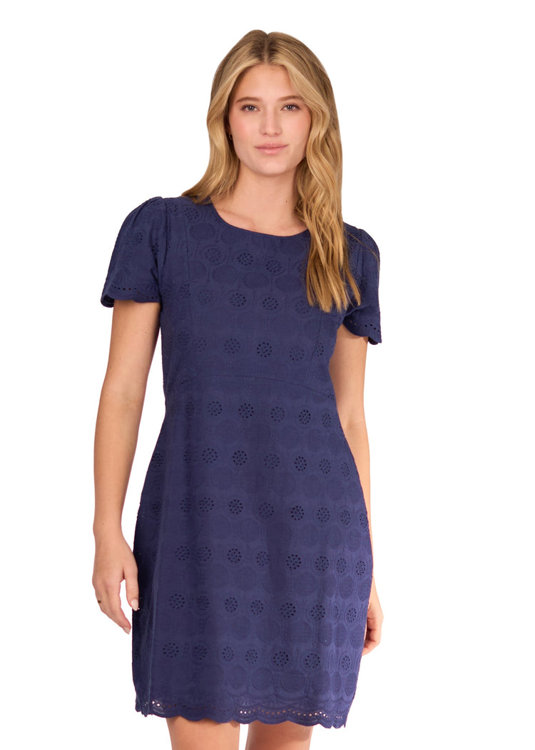 A blonde woman wearing the Navy Eyelet Short Sleeve Dress on a white background.