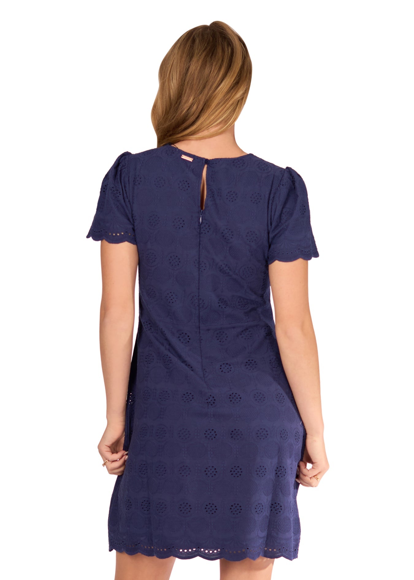 The back of a blonde woman wearing the Navy Eyelet Short Sleeve Dress on a white background.