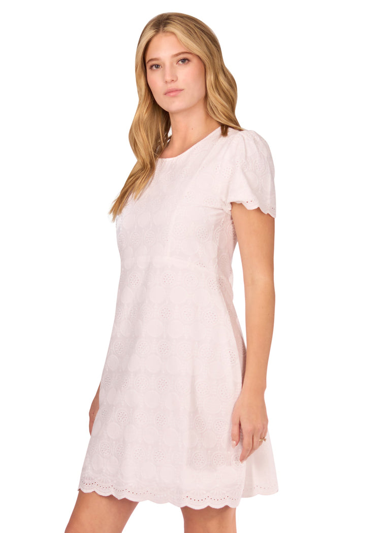 The side of a blonde woman wearing the White Eyelet Short Sleeve Dress on a white background.