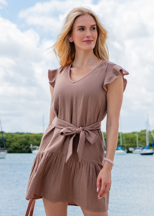 Woman wearing a brown dress with a blurred background of water and boats