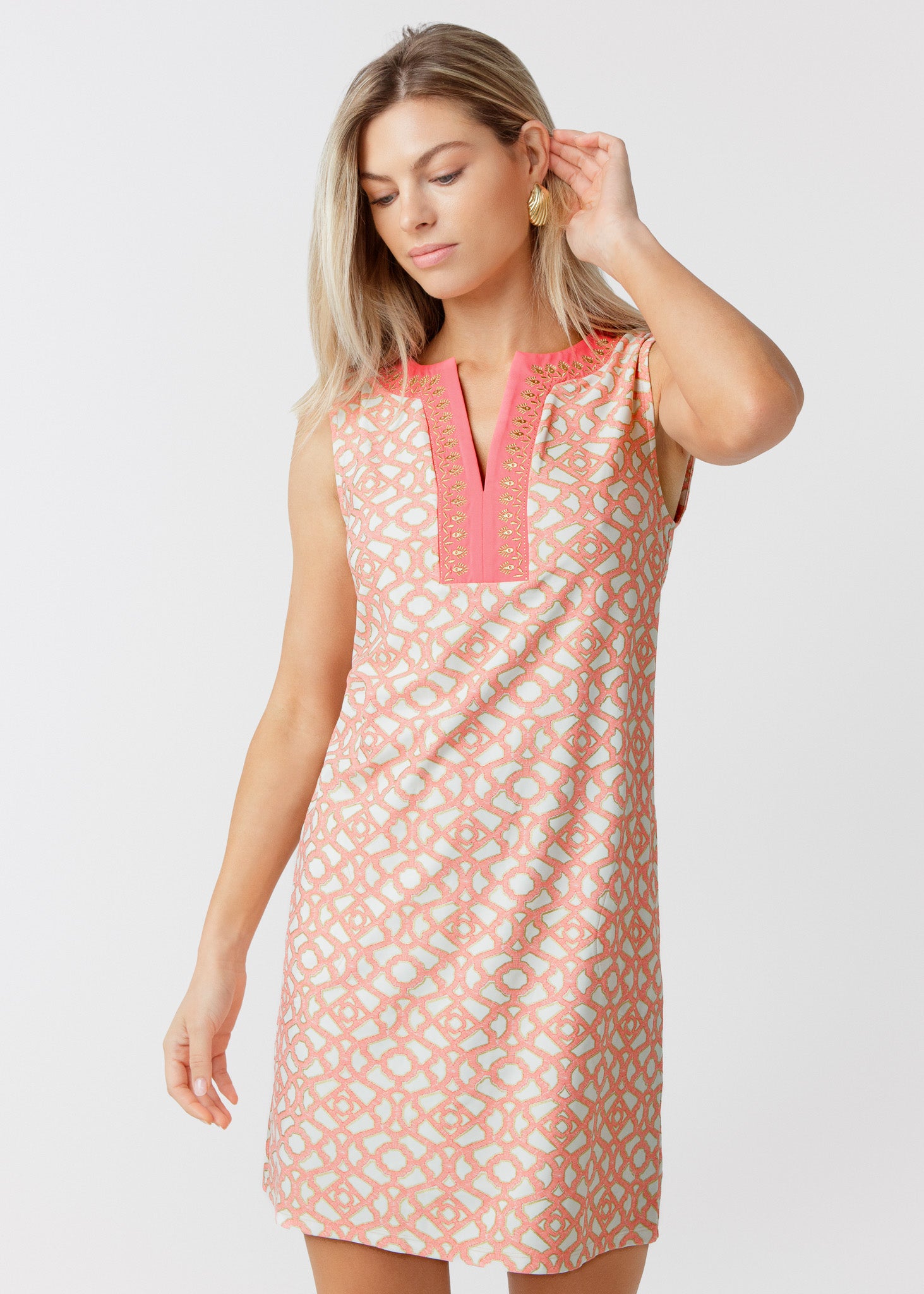 Woman wearing a patterned dress with pink accents on a white background